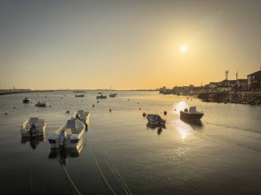 Some fishing boats moored at the pier in Sao Jacinto at sunset in Aveiro, Portugal