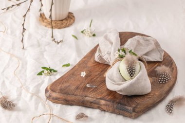 Paskalya kahvaltısı sofrasında yumurta ve paskalya tavşanı peçetesi. Tavşan kulaklı peçetede modern doğal boyalı yumurta, klasik tabakta çiçekler. Kırsal Paskalya masa dekorasyonları