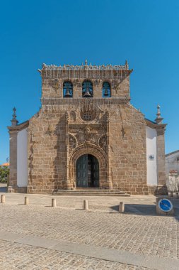 Facade of the sixteenth century Gothic Manueline church with a three bells belfry, in the town of Vila Nova de Foz Coa, Portugal clipart