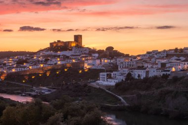 Sunset landscape in Mertola. Medieval city called Mertola in Alentejo region in south Portugal. Medieval castal on top of the hill in center of city. clipart