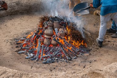 AMARANTE, PORTUGAL - APRIL 30, 2022: Stage of covering with soil of the bonfire with the pieces of clay piled up during the cooking process of the black clay of Gondar on circa april, 2022 in Amarante, Portugal. clipart