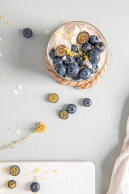 Yaban mersinli, limonlu ve hindistancevizli yulaf ezmesi ve açık mavi ahşap tezgahın üzerinde sağlıklı yaban mersinli limon. Üst görünüm