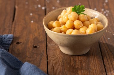 Maydanoz yaprağıyla dekore edilmiş, seramik bir kasede nohut pişirilmiş, yemeye hazır.