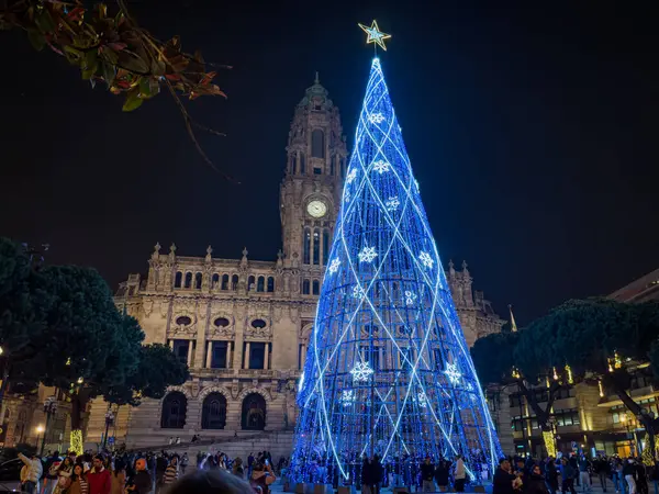 Porto, Portekiz - 9 Aralık 2023. Avenida dos Aliados ve Belediye Binası 'nın gece sahnesi Noel ağacıyla. Yöre sakinleri ve ziyaretçiler Noel ışıklarını ve belediye binasının önündeki büyük Noel ağacını görmek için caddelerde yürüyorlar.