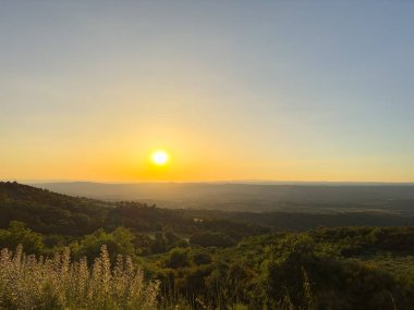 Altın gün batımı, kayalık tepelerin ve yemyeşil yemyeşilliklerin arasına kurulmuş sakin bir köyün üzerine ılık bir ışık saçıyor. Linhares da Beira, Portekiz