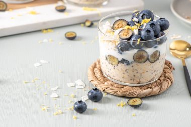 Yaban mersinli, limonlu ve hindistancevizli yulaf ezmesi ve açık mavi ahşap tezgahın üzerinde sağlıklı yaban mersinli limon. Sağlıklı yeme ve beslenme kavramı.
