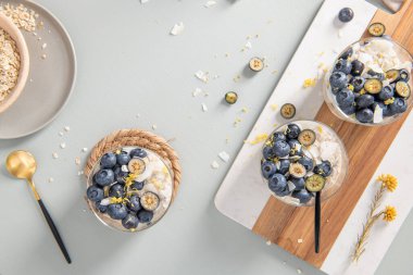 Yaban mersinli, limonlu ve hindistancevizli üç sağlıklı yulaf ezmesi ve açık mavi ahşap tezgahta. Üst görünüm