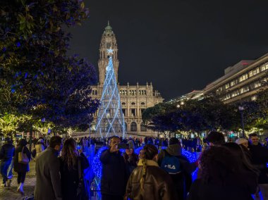 Porto, Portekiz - 6 Aralık 2023. Avenida dos Aliados ve Belediye Binası 'nın gece sahnesi Noel ağacıyla. Yöre sakinleri ve ziyaretçiler Noel ışıklarını ve belediye binasının önündeki büyük Noel ağacını görmek için caddelerde yürüyorlar.