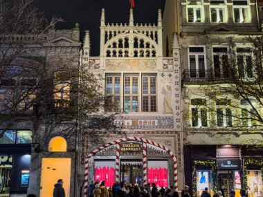 Porto, Portugal - December 9, 2023. Night scene of crowd of people in front of monumental facade of Library Lello and Irmao, one of the major tourist attractions for Harry Potter fans, Carmelitas street, Oporto center. clipart