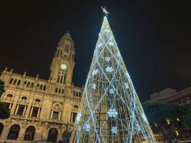 Porto, Portekiz - 9 Aralık 2023. Avenida dos Aliados ve Belediye Binası 'nın gece sahnesi Noel ağacıyla. Yöre sakinleri ve ziyaretçiler Noel ışıklarını ve belediye binasının önündeki büyük Noel ağacını görmek için caddelerde yürüyorlar.