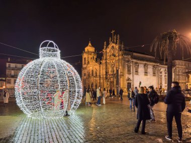 Porto, Portekiz - 9 Aralık 2023. Aslan çeşmesinin gece sahnesi. Yöre sakinleri ve ziyaretçiler Noel ışıklarını ve belediye binasının önündeki büyük Noel ağacını görmek için caddelerde yürüyorlar.