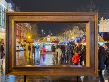 Porto, Portugal - December 9, 2023. A cozy christmas market in Batalha square, stall selling the typical handicraft and food. Stall adorned with warm lights and holiday decorations captures the festive spirit of the season as visitors browse nearby. clipart