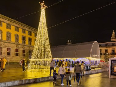 Porto, Portekiz - 9 Aralık 2023. Kordoarya meydanının gece manzarası. Yöre sakinleri ve ziyaretçiler Noel ışıklarını ve belediye binasının önündeki büyük Noel ağacını görmek için caddelerde yürüyorlar.