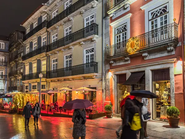 Porto, Portekiz - 9 Aralık 2023. Porto 'daki Rua das Flores ya da Flores caddelerinin Noel süslemeleriyle süslendiği gece sahnesi. Yöre sakinleri ve ziyaretçiler Noel ışıklarını görmek için sokaklarda yürüyorlar.