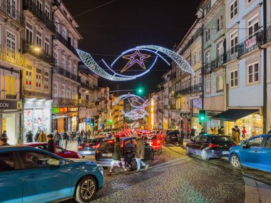 Porto, Portekiz - 9 Aralık 2023. Rahipler caddesinin gece manzarası. Yöre sakinleri ve ziyaretçiler Noel ışıklarını ve belediye binasının önündeki büyük Noel ağacını görmek için caddelerde yürüyorlar.