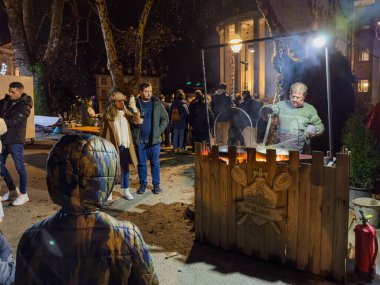 Porto, Portugal - December 9, 2023. Night scene of cordoaria christmas market. Man making crepes traditionally made in a fire clipart