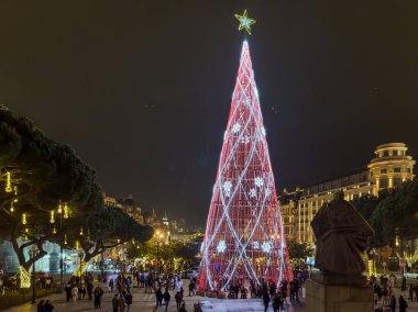 Porto, Portekiz - 9 Aralık 2023. Avenida dos Aliados ve Belediye Binası 'nın gece sahnesi Noel ağacıyla. Yöre sakinleri ve ziyaretçiler Noel ışıklarını ve belediye binasının önündeki büyük Noel ağacını görmek için caddelerde yürüyorlar.