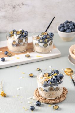 Yaban mersinli, limonlu ve hindistancevizli yulaf ezmesi ve açık mavi ahşap tezgahın üzerinde sağlıklı yaban mersinli limon. Sağlıklı yeme ve beslenme kavramı.