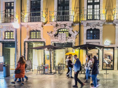 Porto, Portekiz - 9 Aralık 2023. Porto 'daki Rua das Flores ya da Flores caddelerinin Noel süslemeleriyle süslendiği gece sahnesi. Yöre sakinleri ve ziyaretçiler Noel ışıklarını görmek için sokaklarda yürüyorlar.