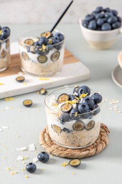 Yaban mersinli, limonlu ve hindistancevizli yulaf ezmesi ve açık mavi ahşap tezgahın üzerinde sağlıklı yaban mersinli limon. Sağlıklı yeme ve beslenme kavramı.