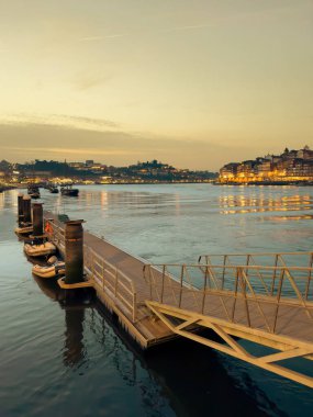 Portekiz 'in Porto kentinin tarihi mimarisini vurgulayan huzurlu bir günbatımı, Douro Nehri' nin üzerine sıcak bir ışık saçar..