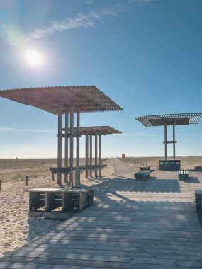 Tahta barınaklar ve banklar Figueira da Foz sahilinde bir sahil boyunca uzanır ve bu popüler sahil beldesine ziyaretçiler için gölge ve rahatlama sağlar..