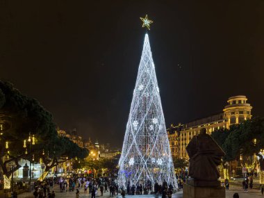 Porto, Portekiz - 9 Aralık 2023. Avenida dos Aliados ve Belediye Binası 'nın gece sahnesi Noel ağacıyla. Yöre sakinleri ve ziyaretçiler Noel ışıklarını ve belediye binasının önündeki büyük Noel ağacını görmek için caddelerde yürüyorlar.