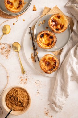 Geleneksel Portekiz kremalı tartları olan Pastel de Nata 'nın bir koleksiyonu vanilyalı fasulye ve söğüt dallarıyla birlikte tabaklar üzerinde düzenlenir. Üst görünüm