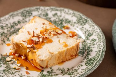 Yakın plan çekimde, Molotof ya da molotof olarak bilinen geleneksel karamelli yumurta akı pudingi bol bol altın şurup serpiştirilir ve dekoratif bir tabakta badem parçaları serpiştirilir.