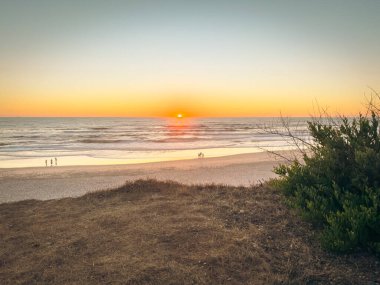 Altın saat Portekiz, Ovar 'daki Sao Pedro de Maceda Sahili' ni resmediyor. Sıcak renkleri yumuşak dalgaları ve engin gökyüzünü yansıtıyor.