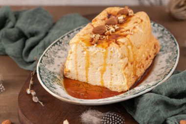 Yumuşak odaklı bir çekim, geleneksel karamelize edilmiş yumurta akı pudingi Molotof ya da molotof olarak bilinen, bol karamelli ve bütün ve doğranmış bademlerle süslenmiş, dekoratif bir tabakta sunar.