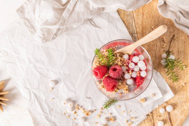 Bir bardak katmanlı ahududu ve chia tohumu pudingi taze ahududu ve ahşap bir tabakta beyaz yaban mersini.