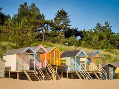 29 June 2019: Wells-Next-The-Sea, Norfolk, England, UK - Bathing huts on the beach, trees behind.
