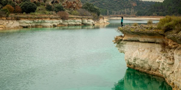 Person alone contemplating the lake from a cliff and enjoying nature in the lagoons of Ruidera, Spain. Traveling alone to relax.