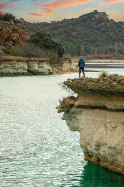 Person alone contemplating the lake from a cliff and enjoying nature in the lagoons of Ruidera, Spain. Traveling alone to relax.