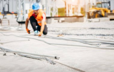 Elektrikçi modern elektrik santraline yerleştirilmeden önce demir gibi kalın bir kabloyu elinde tutuyor.