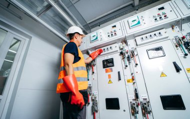 Erişkin elektrikçi mühendisi sigorta kutusunda test ve vida ekipmanı ve tabletteki verileri kullanarak modern elektrik santralinin onarımını otomatik kontrol dolabı.