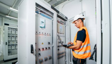 Erişkin elektrikçi mühendisi sigorta kutusunda test ve vida aletleri ve modern elektrik santralinin tamiri. Otomatik kontrol dolabı