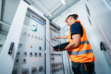 Erişkin elektrikçi mühendisi sigorta kutusunda test ve vida aletleri ve modern elektrik santralinin tamiri. Otomatik kontrol dolabı