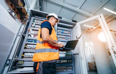 Erişkin elektrikçi mühendisi sigorta kutusunda test ve vida aletleri ve modern elektrik santralinin tamiri. Otomatik kontrol dolabı
