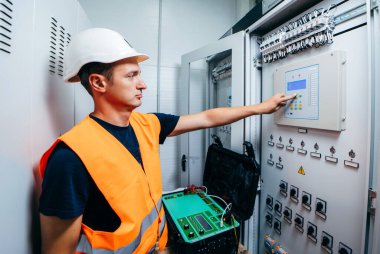 Adult electrician builder engineer testing and screwing equipment of device for secondary current and voltage testing of relay protection and automation devices of modern electricity power station. clipart