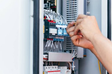 Koruyucu kasklı elektrikçi yüksek voltajlı elektrik hatları üzerinde çalışıyor. Elektrik şebekesine hizmet eden çok yetenekli işçiler. Güç kuleleri olan modern enerji santrali