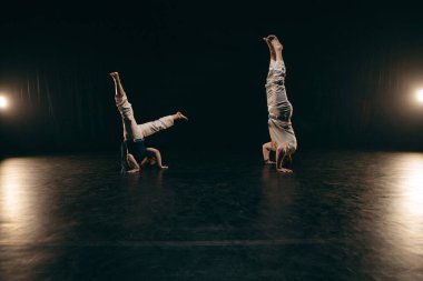 Siyah arka planda Capoeira eğitimi alan iki savaşçı.