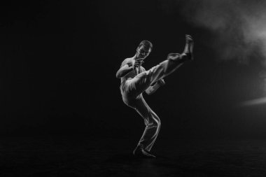 Erkek avcı uçakları siyah arka planda capoeira eğitimi alıyor.