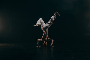 Erkek avcı uçakları siyah arka planda capoeira eğitimi alıyor.