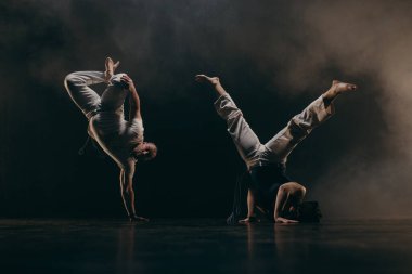 Siyah arka planda Capoeira eğitimi alan iki savaşçı.