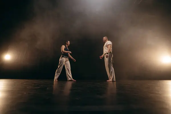 stock image Couple of fighters training capoeira on black background