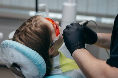 Dişçi bir kıza implant yerleştiriyor.