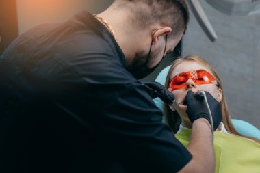 Dişçi bir kıza implant yerleştiriyor.