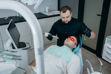 Dişçi, erkek hastanın dişlerini modern 3D tarama makinesiyle tarıyor.